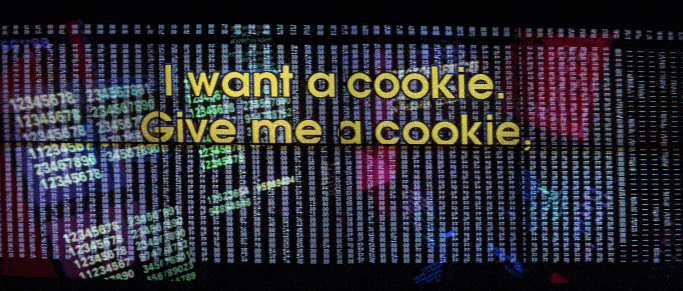 Animated clip from the seminal 1995 film Hackers, featuring a cartoon image of Cookie Monster’s head eating cookies, superimposed on columns of illuminated numbers; text states I want a cookie, give me a cookie now.